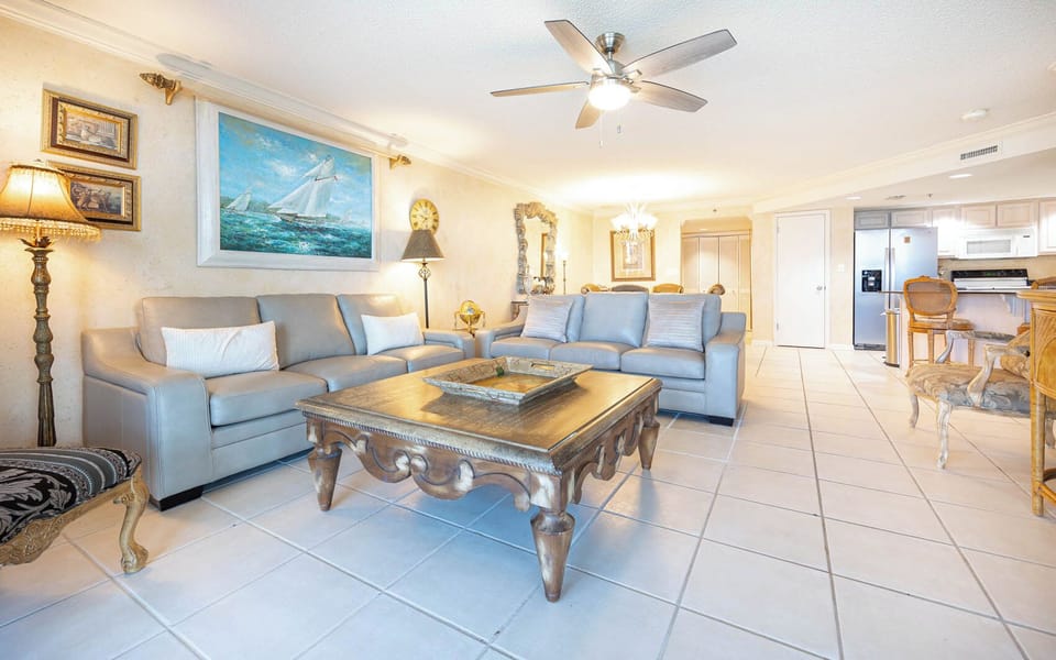 Bright living area features comfortable leather sofas, an ornate coffee table, and a view towards the dining area