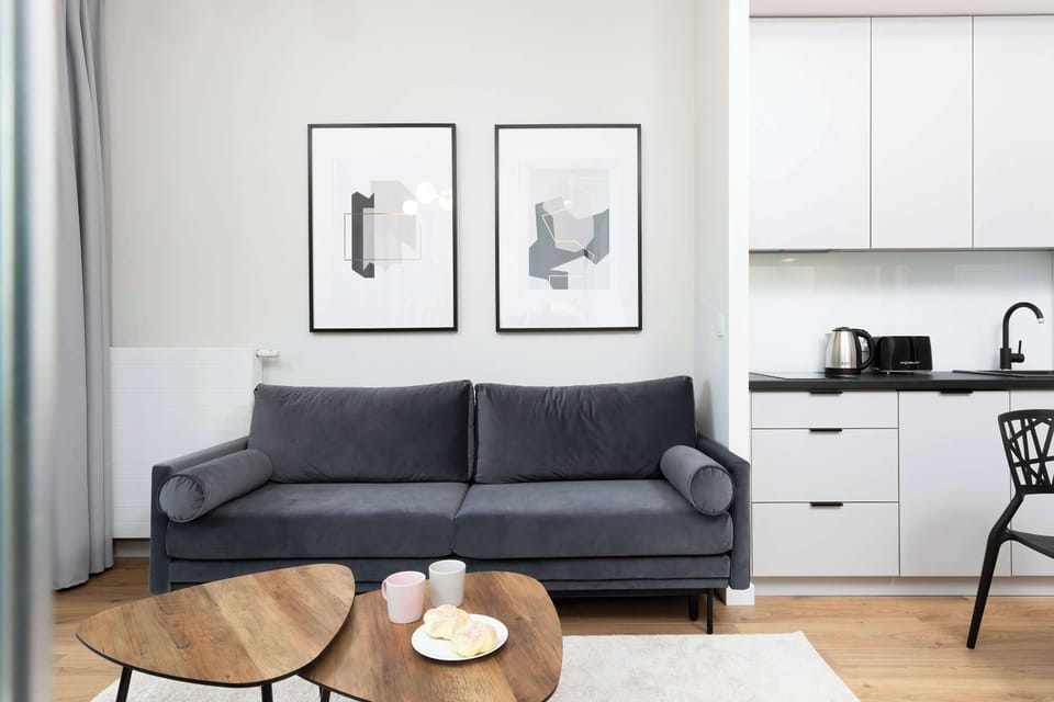 A bright, spacious living room with a sofa, coffee table, and a dining area near large balcony windows.