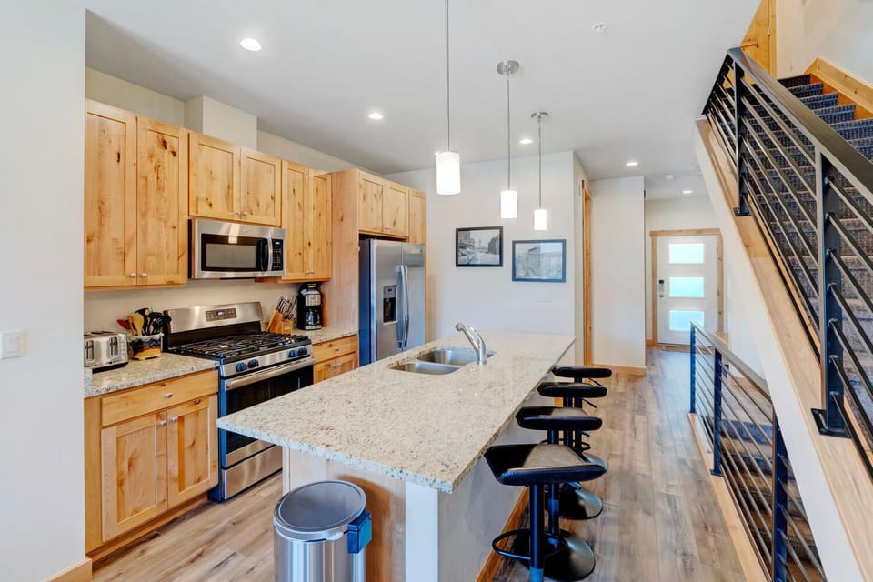 Kitchen with Island, Stools, Refrigerator, Microwave, and the Stairwell
