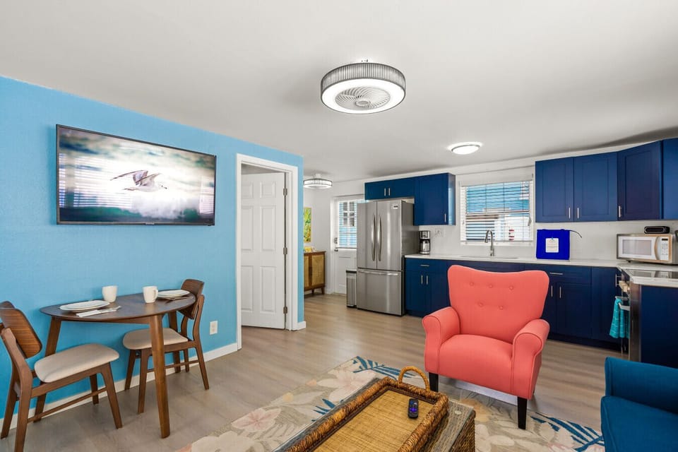 Siesta Key seaside escape featuring a coral chair, bright dining corner & mounted TV—designed for effortless comfort and easy coastal flow.