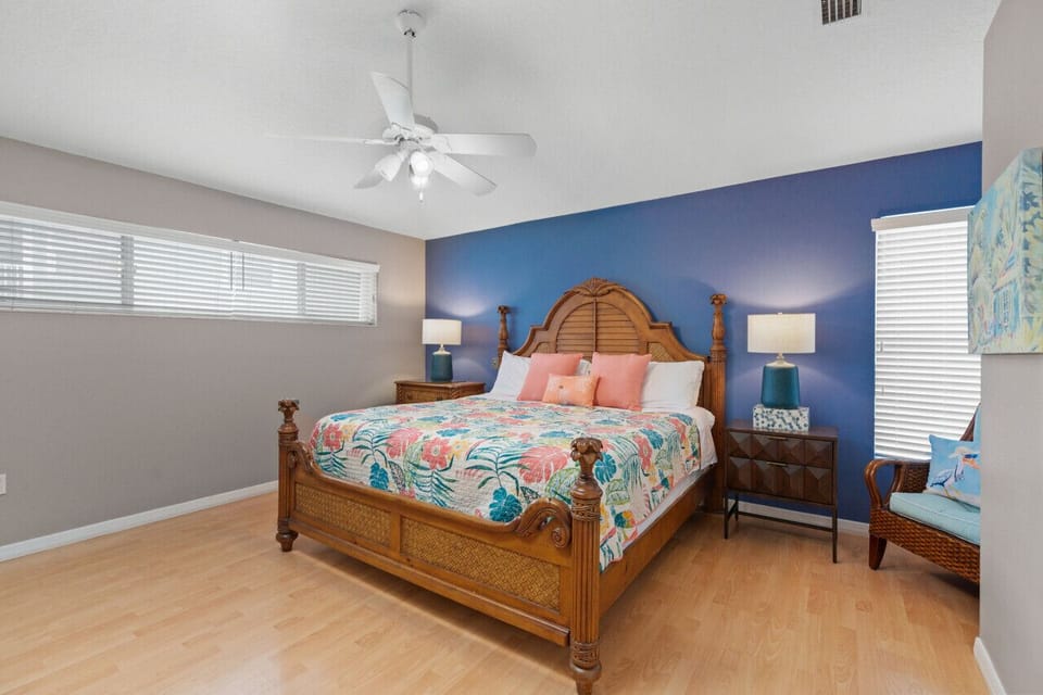 Siesta Key master retreat featuring a comfortable queen bed, tropical quilts, and a striking blue accent wall—an inviting, stylish sanctuary for a restful night after the beach.