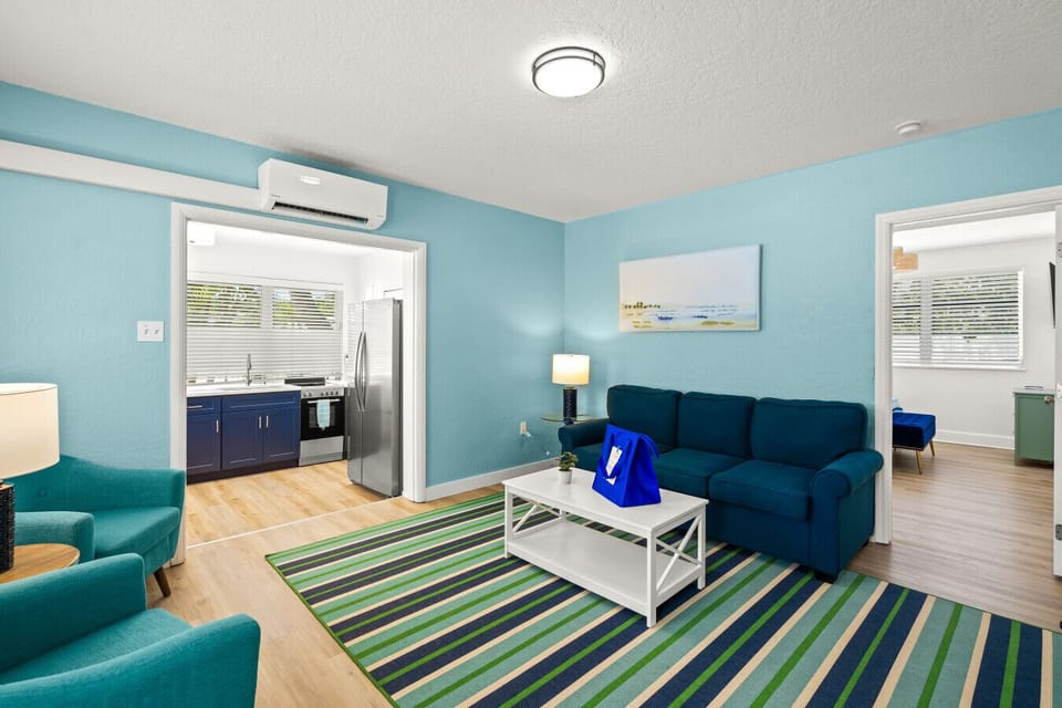 Siesta Key seaside escape featuring teal seating, a beach-inspired rug, and an open-concept kitchen—crafted for relaxed comfort and effortless coastal living.