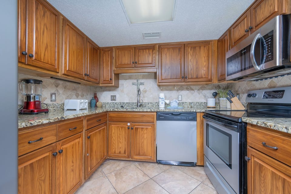 The fully-equipped kitchen features rich wooden cabinets, granite countertops, and modern appliances
