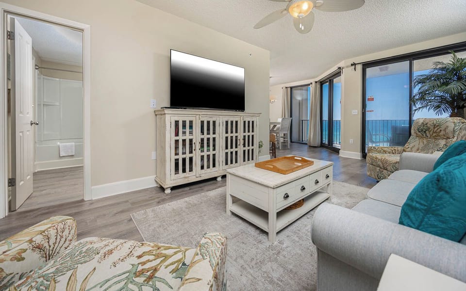 Relax in the inviting living area with a large TV, comfortable seating, sofa with queen sleeper, and beachfront views