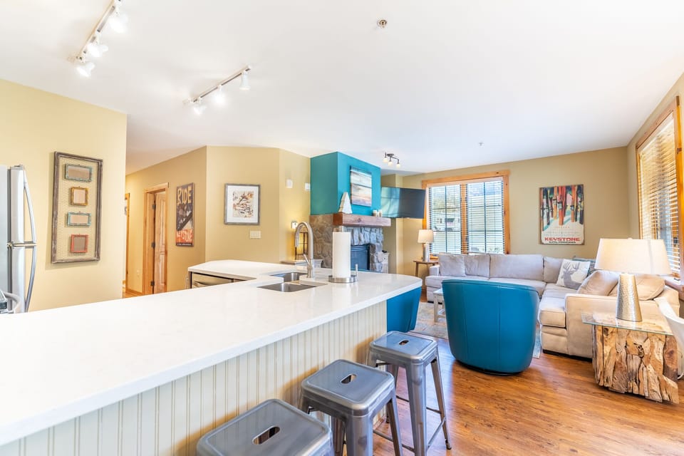 You'll love this open-concept space where vibrant blue accents and warm wood tones create the perfect atmosphere for cooking and relaxing together.