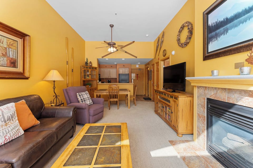 Relax in your cozy living room with leather seating, stone fireplace, and mountain views creating the perfect retreat.
