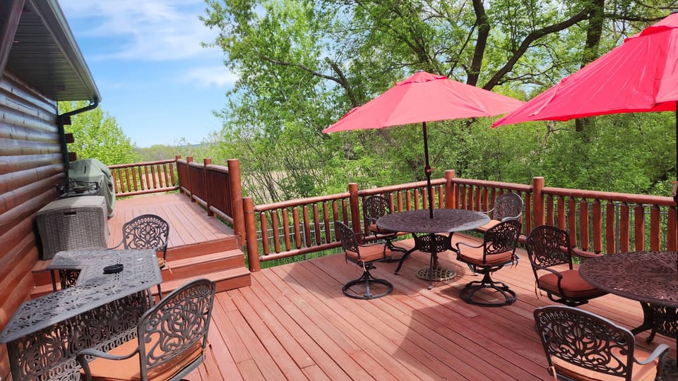 Large wraparound deck with seating, grill, and wooded views