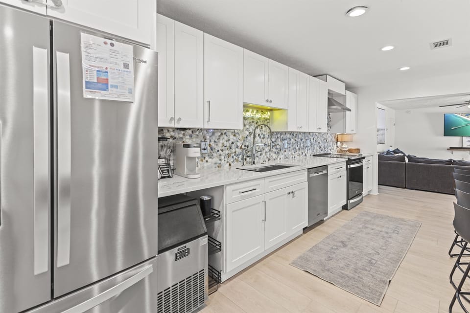 Your sleek modern kitchen features stainless steel appliances and pristine white cabinetry, perfect for preparing memorable meals during your stay.