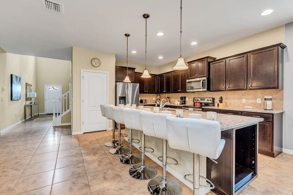 The kitchen adorned with wooden cabinets and a counter bar table exudes rustic elegance, blending natural charm with modern functionality for a warm and inviting culinary space.