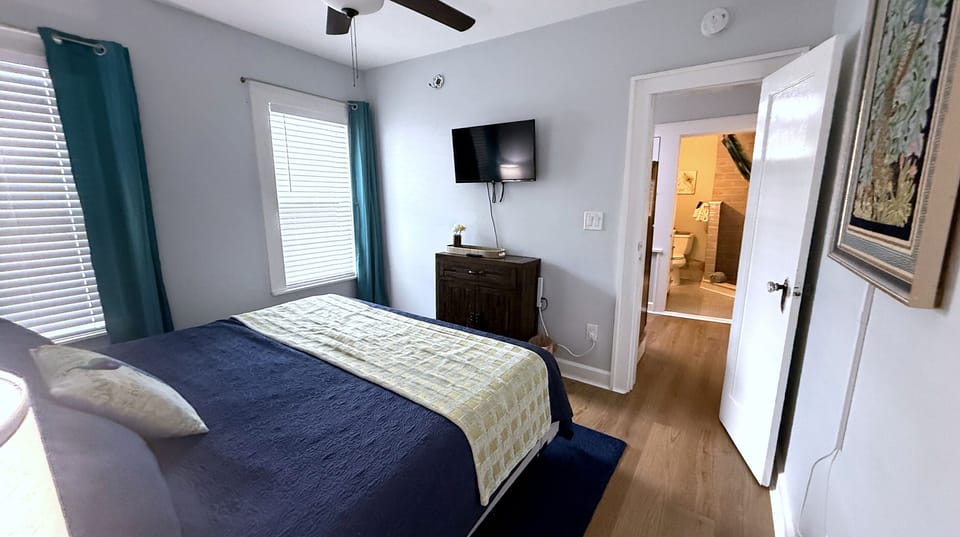 Bedroom opens to kitchen and bathroom with smart TV across and drawers for storage