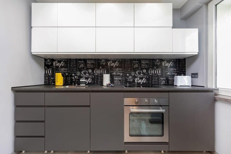 A modern kitchenette with white and black cabinets, geometric tiles, and a functional countertop.