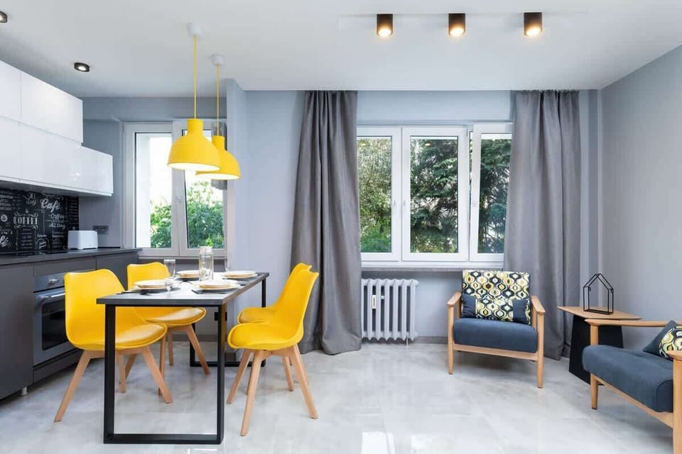A well-lit living room with a comfortable sofa and stylish yellow armchairs arranged around a glass coffee table.