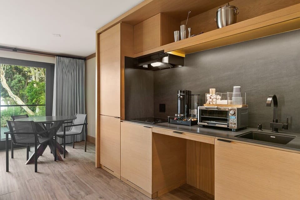 Kitchenette equipped with a ninja blender, garbage disposal, nespresso bar station, toasters oven, microwave, flatware, dinnerware, coffee cups, and bottle opener