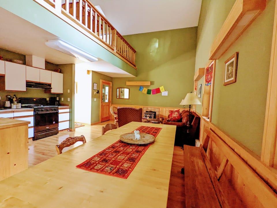 Large dining table adjoins kitchen with large deck just behind. 