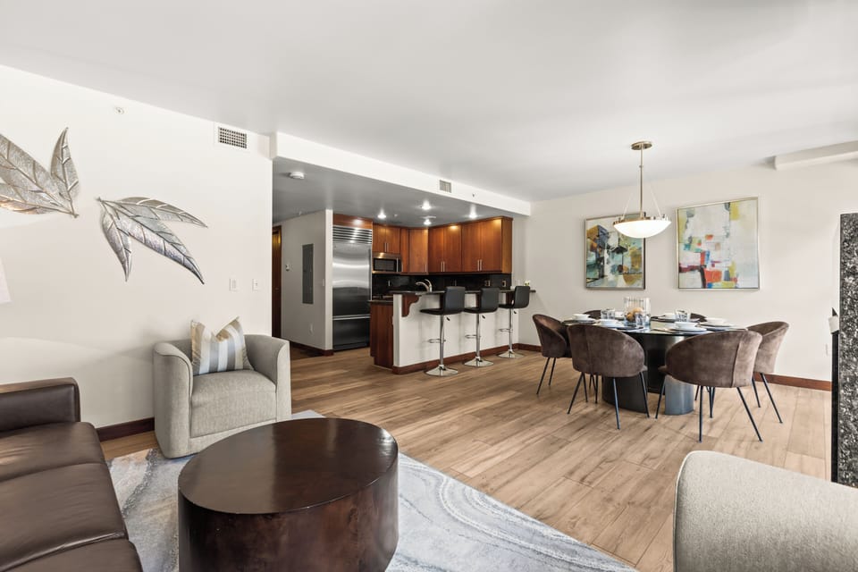 Relax in your stylish open-plan living space featuring warm wood floors, contemporary art, and a fully equipped kitchen.