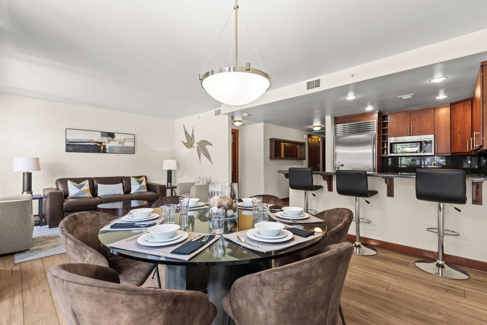 Gather around this elegant dining table for memorable meals, with sleek kitchen counter seating and warm living space perfect for relaxing together.