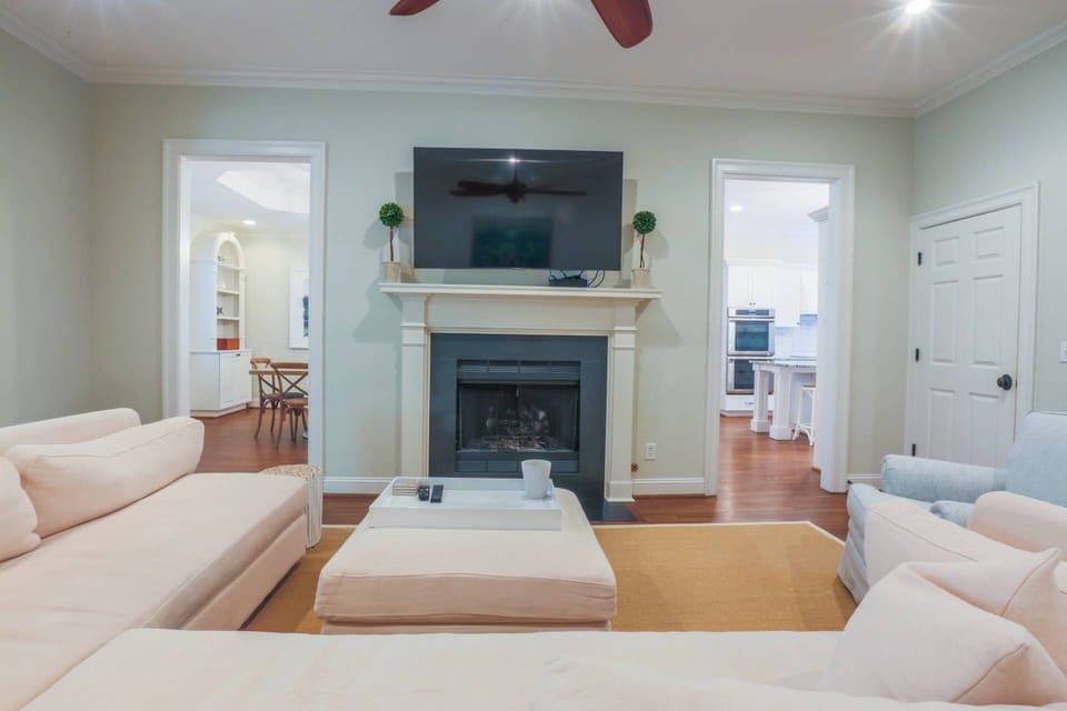 The living room features a large screen cable TV, spacious sectional and ceiling fan.