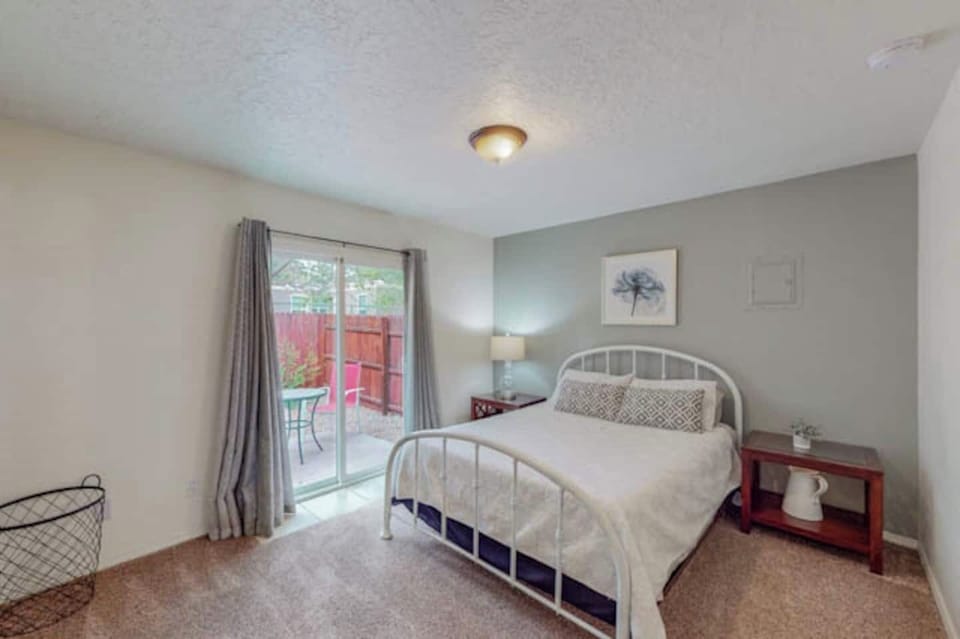 Bedroom with queen bed has a sliding glass door that opens onto a private patio space