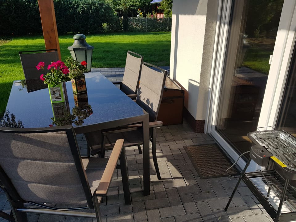 überdachte Terrasse mit Stühlen für 6-7 Personen und Elektrogrill
