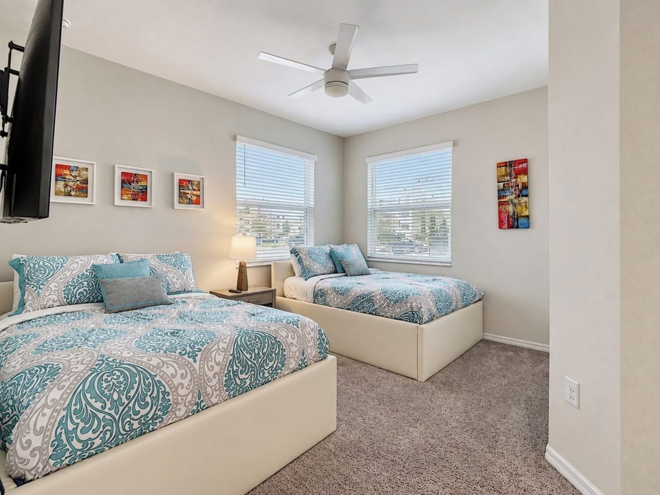Bright bedroom with two comfortable beds and ceiling fan