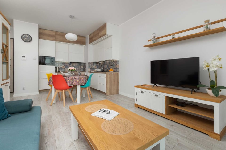 Another angle of the living room, showing the TV unit, wooden coffee table, and a shelf with decorations. The space is compact yet stylish.