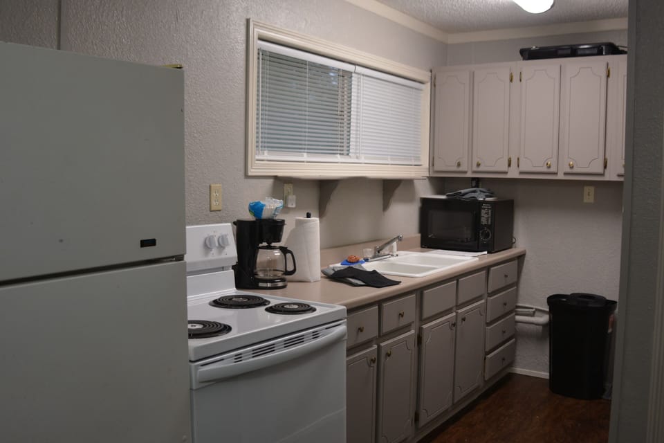 Kitchen has microwave, sink, range and full size refrigerator / freezer. 