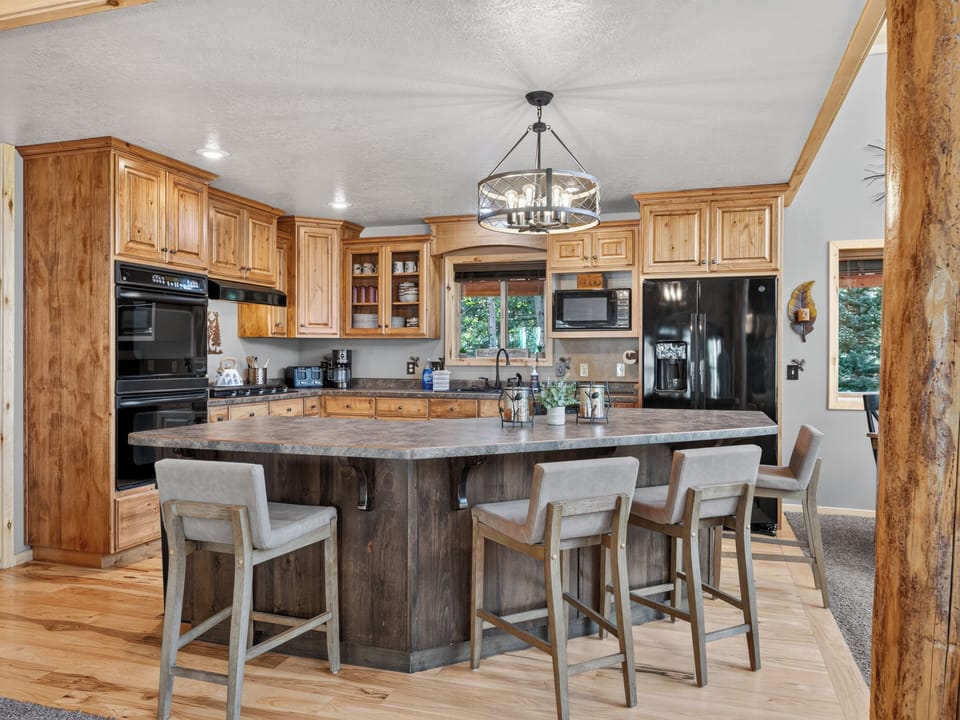 Gather around the spacious island in this fully-equipped kitchen, where rustic wood beams and warm cabinetry create the perfect setting for preparing meals and making memories together.