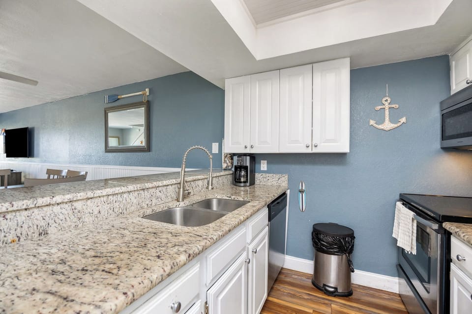 Your coastal-themed kitchen welcomes you with calming blue walls, granite counters, and nautical charm. Perfect for morning coffee or preparing seaside meals.
