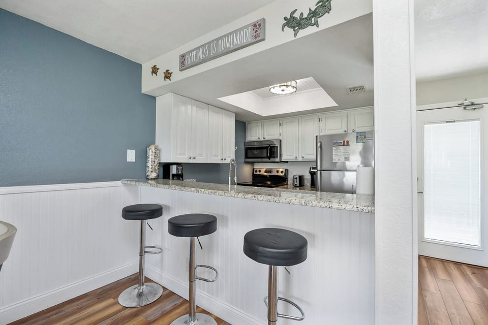 Your coastal-inspired kitchen awaits with granite countertops, modern appliances, and a breakfast bar perfect for morning coffee.