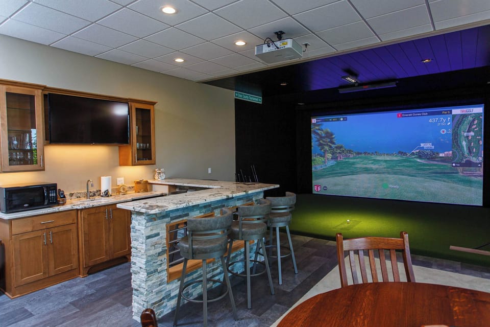 Finished walkout basement is a entertainment center with golf simulator, bar, large screen TV and fireplace.