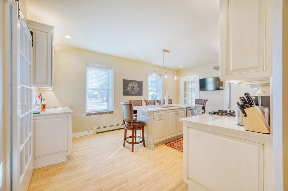 Fully stocked kitchen with beverage center, island with sink, and TV.
