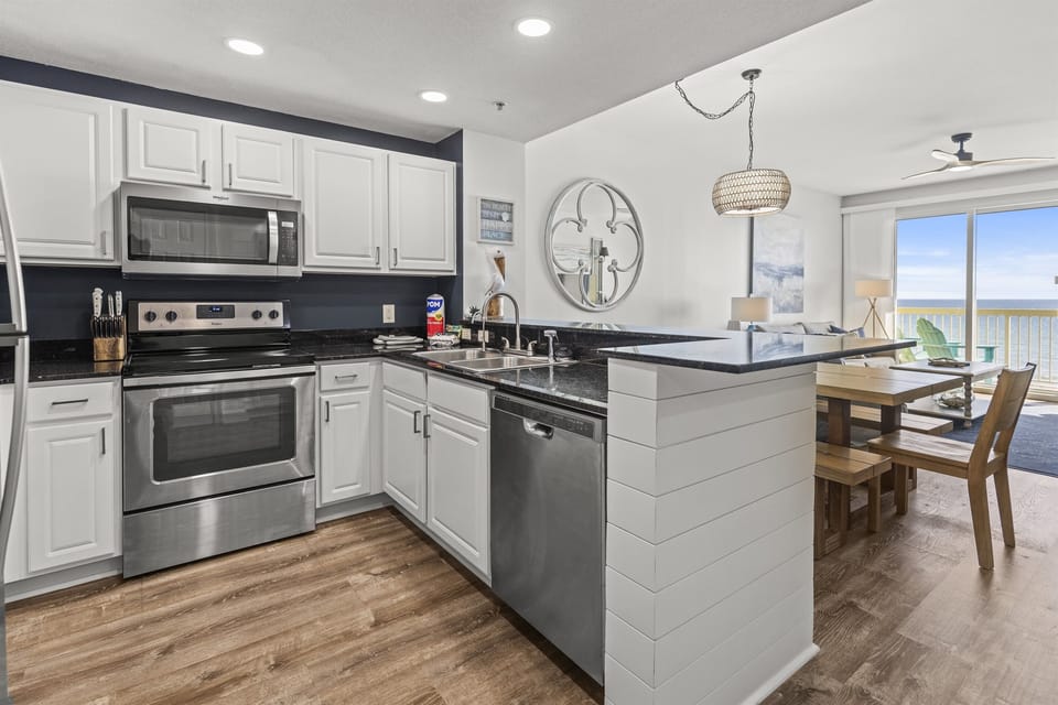 Your fully equipped kitchen features granite counters, stainless appliances, and an island perfect for morning coffee with ocean views.