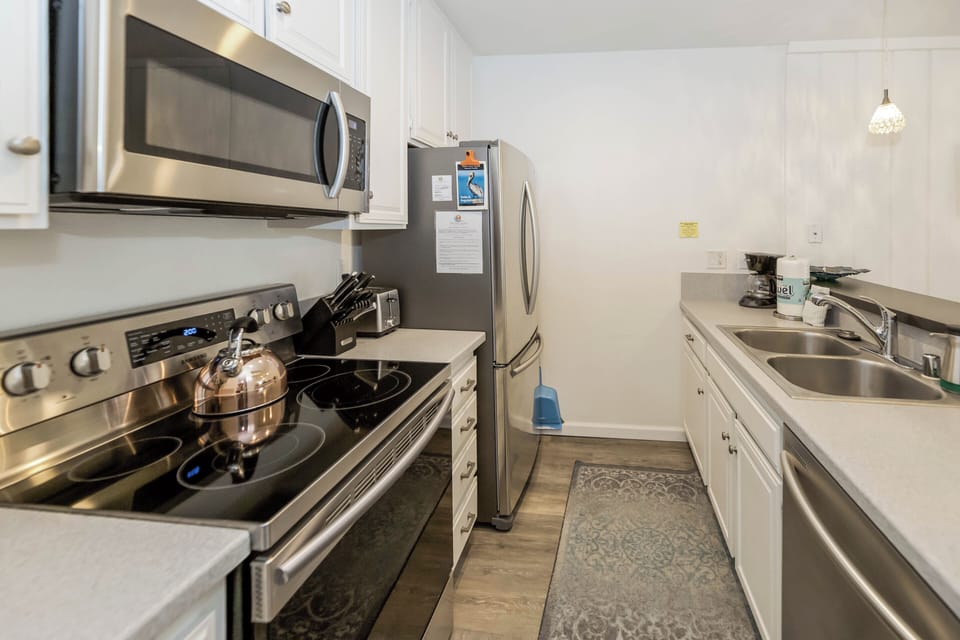 Remodeled kitchen features new wood-look porcelain floors, quartz counter tops, and stainless steel appliances.