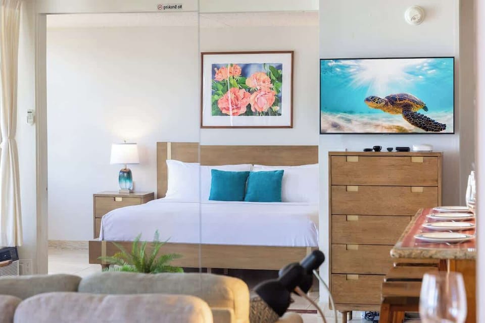 Sunlit bedroom w/ warm wood tones & a welcoming bed styled w/ pops of blue.
