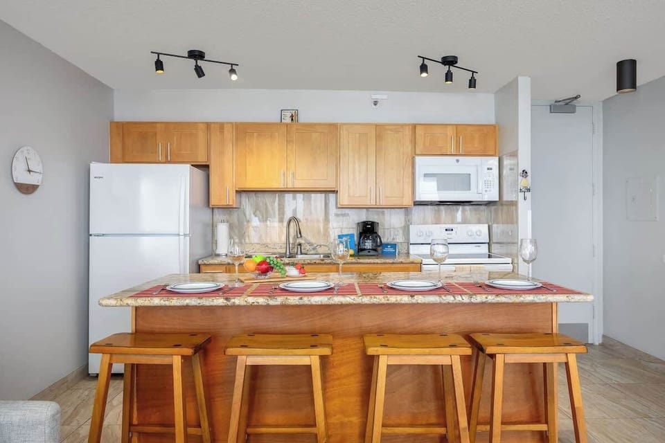 Fully equipped kitchen w/ wood cabinetry & bar seating for easy meal prep.
