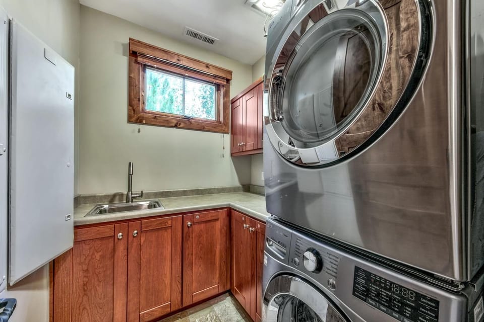 Your dedicated laundry room features stainless steel washer and dryer, rich wood cabinetry, and a convenient utility sink for all your washing needs.