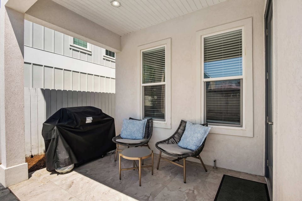 Cook outdoor meals on the covered patio space, equipped with a outdoor BBQ grill, seating, and side table.
