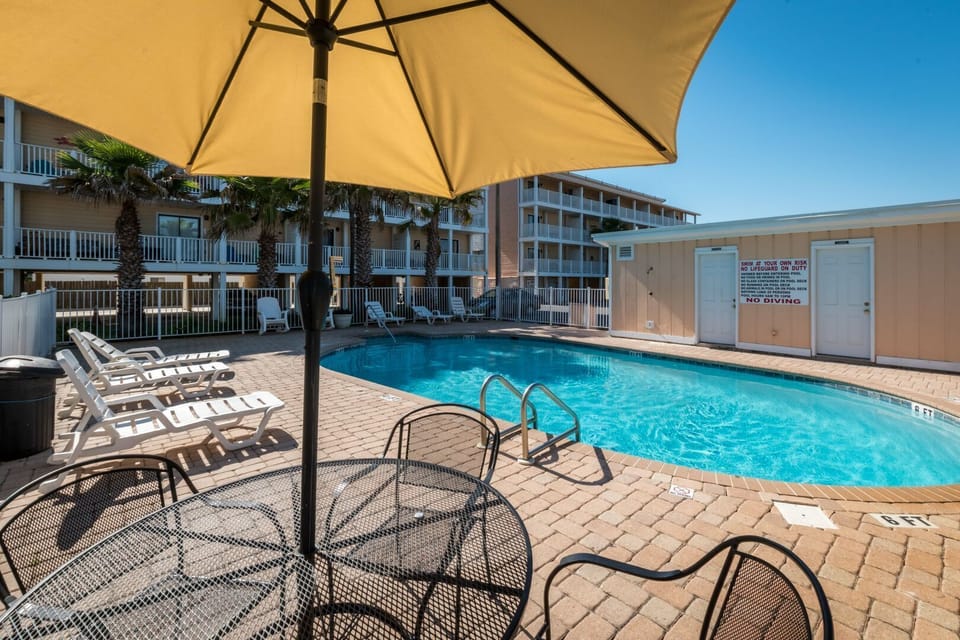 Sparkling pool with tables, chairs, and umbrellas