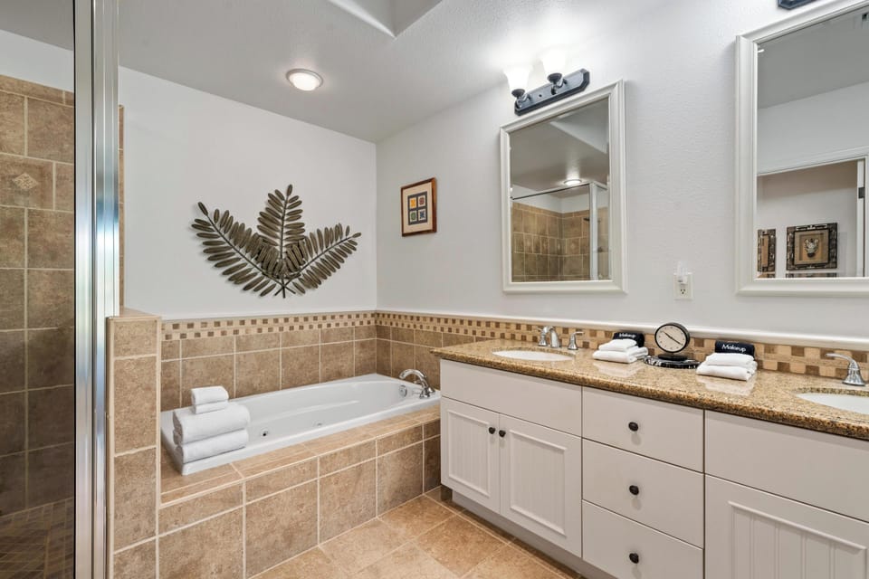 Ensuite primary bathroom with double vanity, walk-in shower, and soaking tub