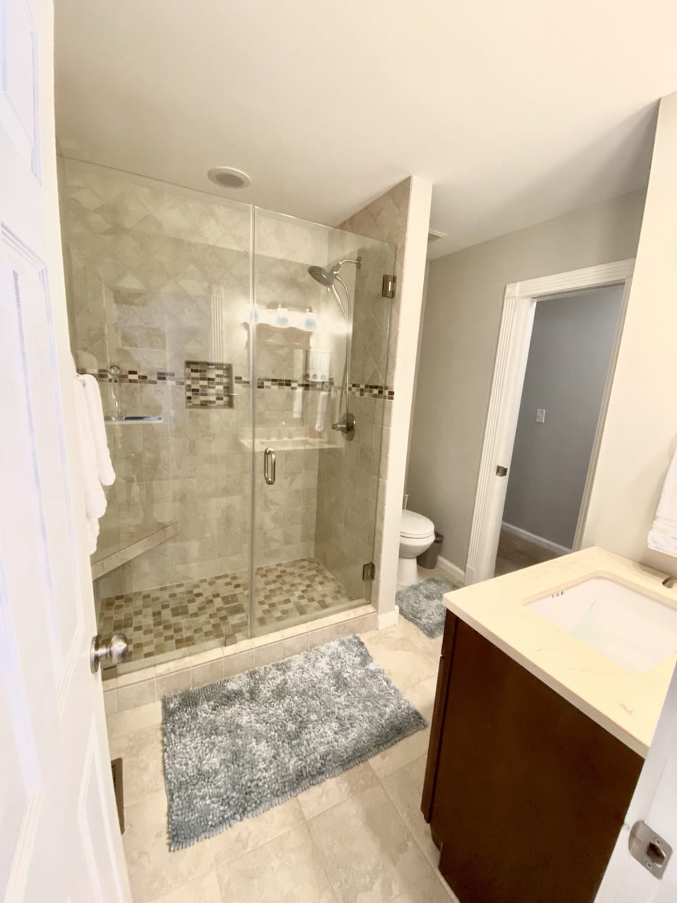 Spacious tiled shower with bench, updated sink, and linen closet