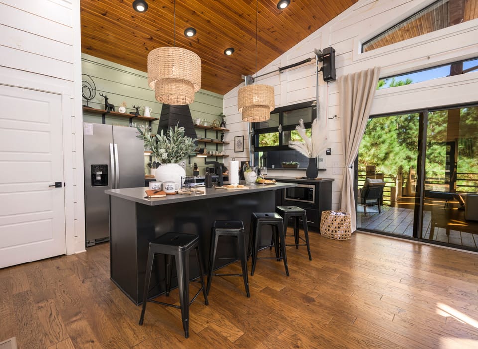 Warm wood ceilings, sculptural pendant lights, and an inviting layout make this kitchen the heart of the cabin