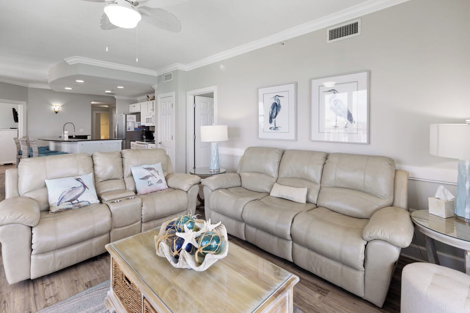 Sink into plush reclining sofas in your coastal living room, where elegant heron artwork and soft blue accents create a serene seaside retreat you'll love coming home to.