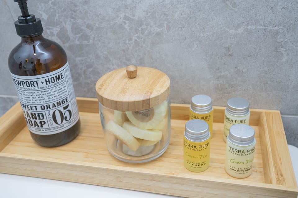 - Bathroom essentials displayed on a bamboo tray for guest convenience   - Fresh toiletries and soap create a welcoming thoughtful touch   - Modern countertop and clean organization elevate the experience