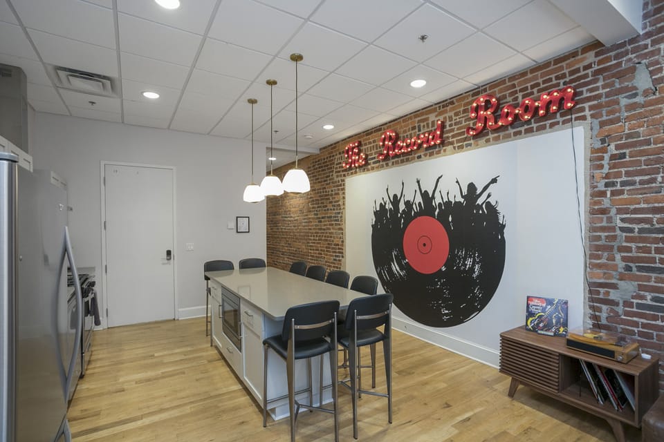 - Record Room wall art creates bold music-inspired style   - Spacious kitchen layout blends creativity with modern comfort   - Pendant lighting and brick walls complete the Nashville vibe