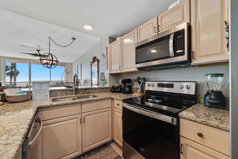 This fully functional kitchen boasts stainless steel appliances, sleek countertops, a decorative backsplash, and ample cabinet storage, ideal for everyday cooking and entertaining.