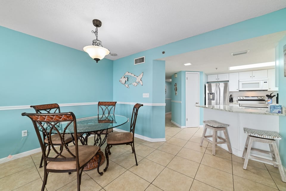 Seamless Entertaining. This bright, open kitchen features a large island with bar seating for 2 and flows directly into the elegant 4-seater dining table—perfect for family gatherings.