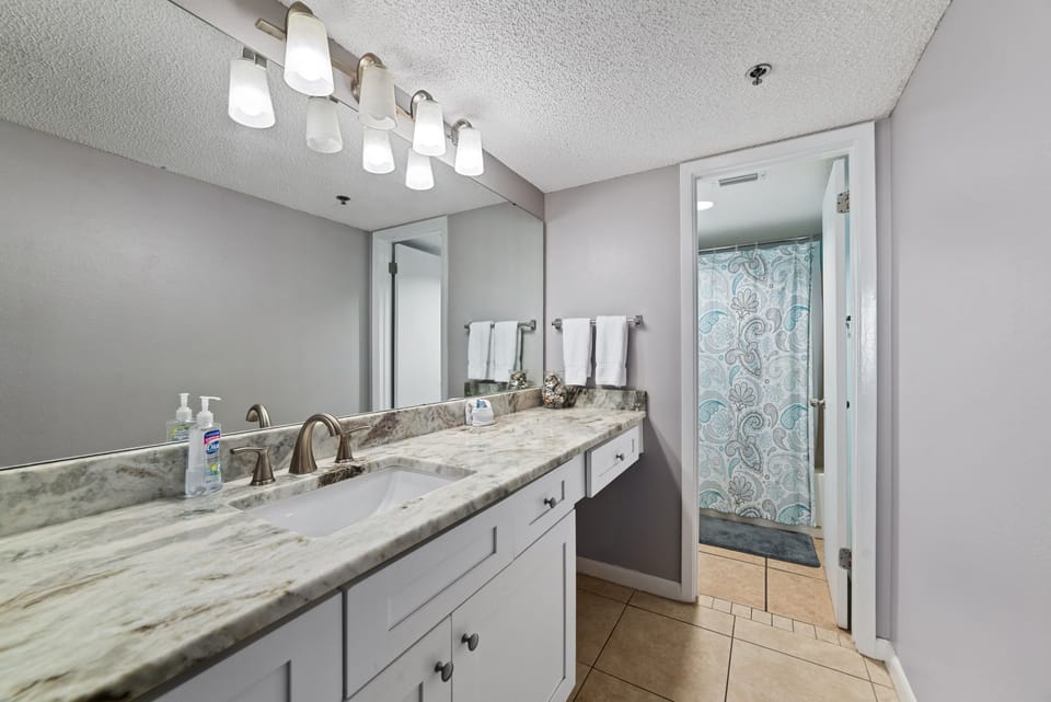 Convenience meets style in the primary bathroom, featuring an updated vanity with granite countertops, ample storage, and a versatile shower-tub combo perfect for all guests.