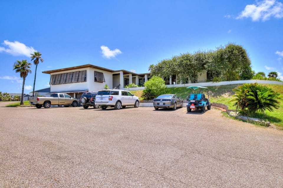 Property exterior with convenient parking area and landscaped grounds under clear blue skies.