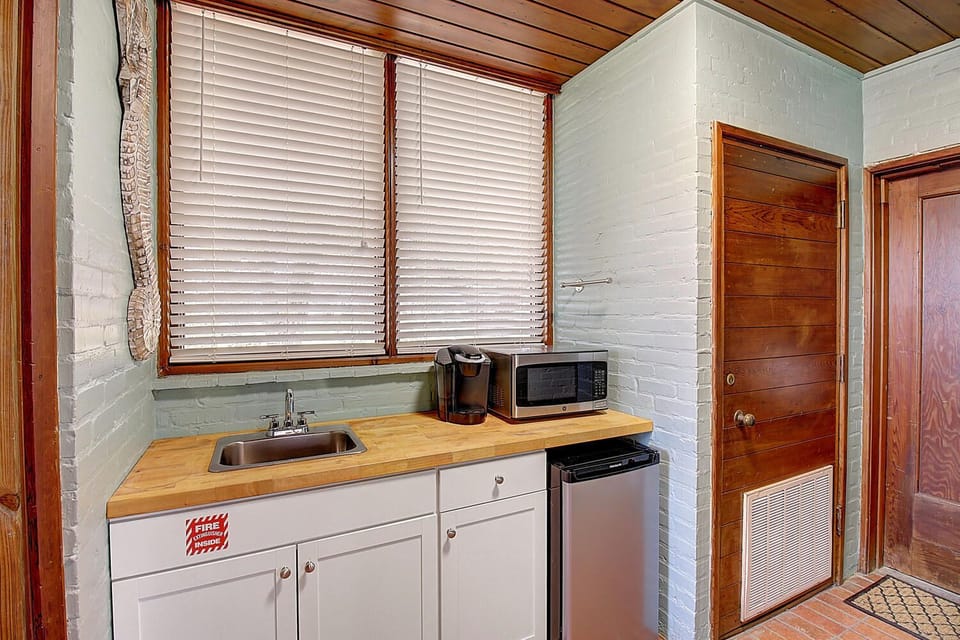 Your compact kitchenette offers everything needed for easy meal prep, with butcher block counters and warm wood details creating a cozy cooking space.