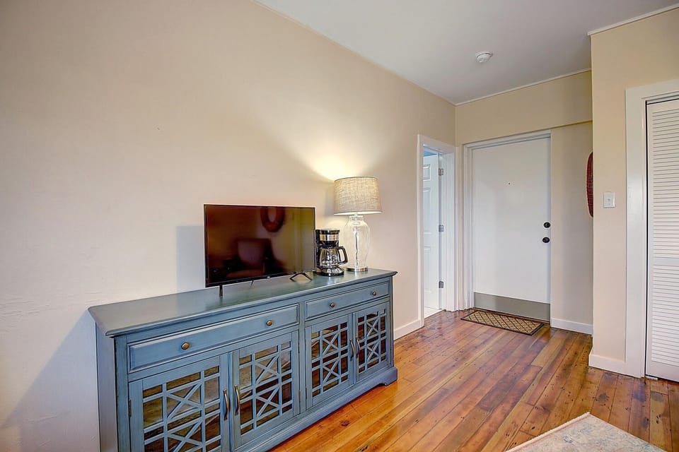 Unwind in your thoughtfully appointed living space, where warm hardwood floors meet elegant blue furniture and modern amenities like your flat-screen TV.